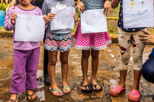 Group of dabnified children showing blank papers where they drew pictures in El Rama, Nicaragua