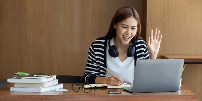 Back to school concept. Young college woman using laptop at library.