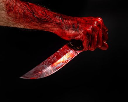 Man holding knife with bloody hand on black background