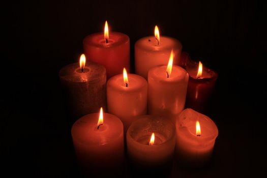 Group of burning candles in different heights and colors