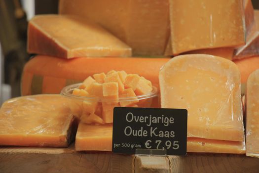 Traditional Dutch cheeses on display on a market stall. Text on tag in Dutch: very old cheese, 500 grams for € 7.95