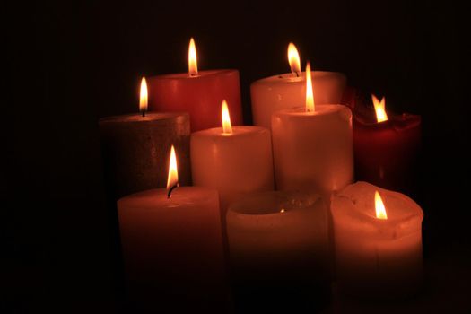 Group of burning candles in different heights and colors
