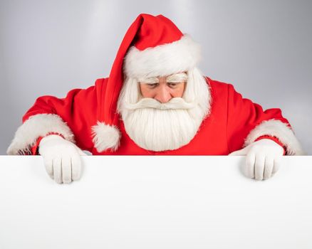 Santa Claus peeks out from behind an ad on a white background. Merry Christmas