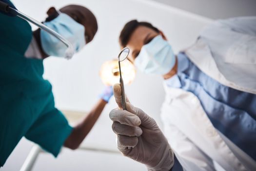 Here comes the dental squad to save the day. Low angle shot of two dentists getting ready to perform a procedure on a patient