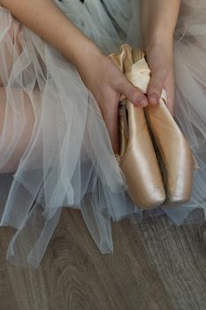 legs of girl dancing ballet with tulle skirt and pink shoes different dance steps wooden floor and white background with copy space