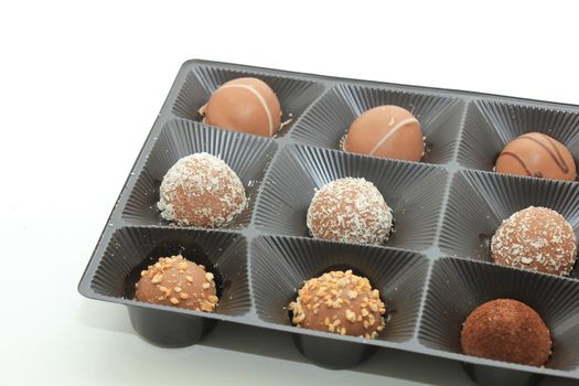 Various chocolates in a tray, bonbons with different topping and filling