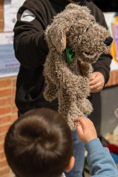 unrecognizable child looking at a stuffed dog puppet