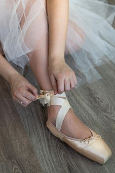 legs of girl dancing ballet with tulle skirt and pink shoes different dance steps wooden floor and white background with copy space