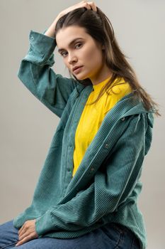 Portrait of attractive beautiful woman sitting with hand in head, looking at camera with pensive expression, wearing casual style jacket. Indoor studio shot isolated on gray background.