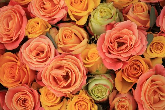 Yellow, orange and pink roses in a floral arrangement at a wedding