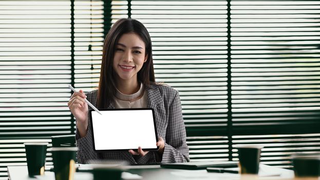 Gorgers female entrepreneur holding and showing digital tablet. Empty screen for your advertise text.