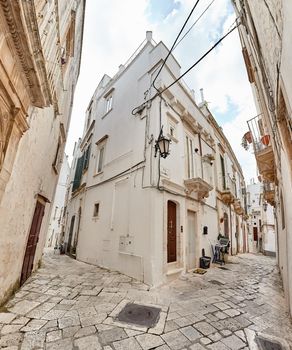 Wonderful architecture of an ancient streets decorated with plants in flowerpots. Downtown, white city Ostuni, Bari, Italy. Tourism, travel concept.