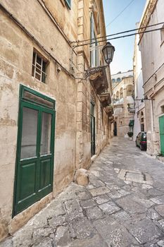 Admirable architecture of an ancient streets decorated with plants in flowerpots and lights. Downtown, white city Ostuni, Bari, Italy. Tourism, travel concept.