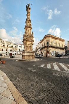 Wonderful architecture of a big square with a great monument, decorated with plants in flowerpots. Downtown, white city Ostuni, Bari, Italy. Tourism, travel concept.
