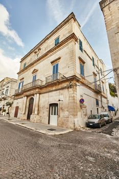 Wonderful architecture of an ancient streets decorated with plants in flowerpots. Downtown, white city Ostuni, Bari, Italy. Tourism, travel concept.