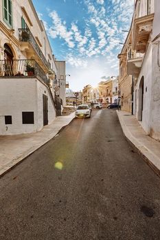 Beautiful architecture of an old streets decorated with plants in flowerpots. Downtown, white city Ostuni, Bari, Italy. Tourism, travel concept.