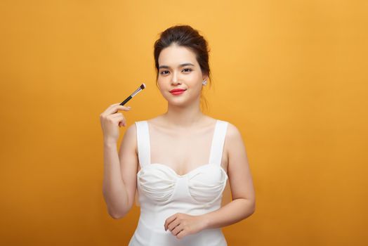 Woman applying make up with brush, isolated. Beauty procedures