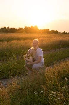 Dad and his blonde daughter are walking and having fun in a chamomile field. The concept of Father's Day, family and nature walks.