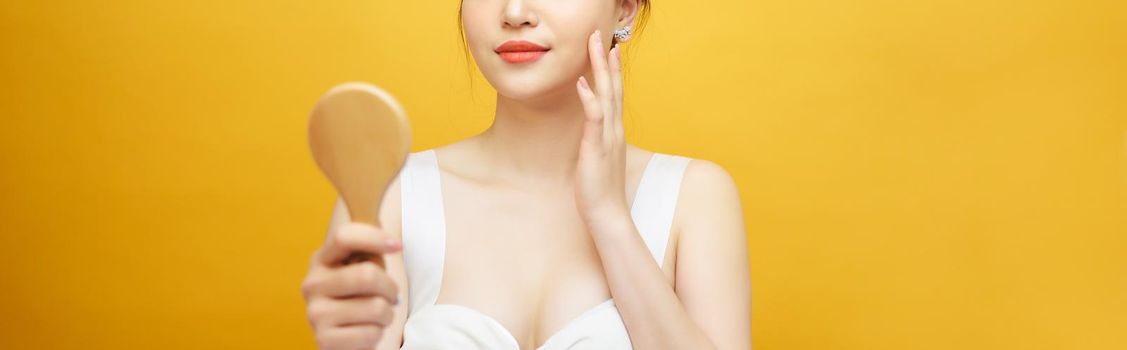 Asian woman holding and looking in classical wooden mirror.