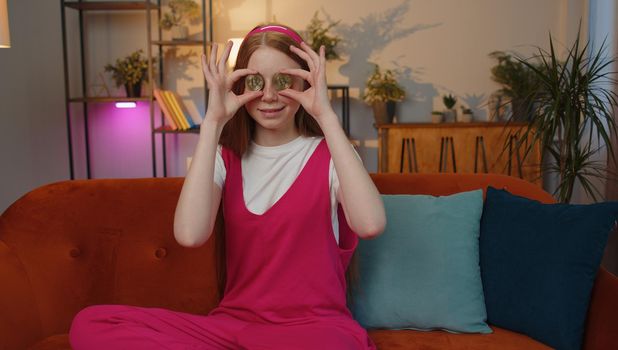 Child girl freelancer holding two gold coins at home, successful developer programmer. Stock trader earning bitcoins after online monitoring trading operations. Increasing wealth, financial prosperity