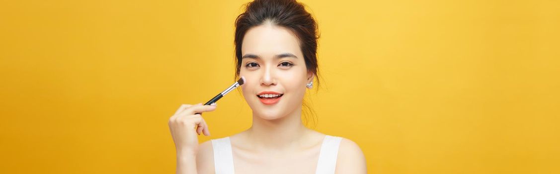 Woman applying make up with brush, isolated. Beauty procedures