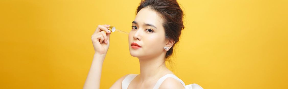 Closeup shot of cosmetic oil applying on young woman's face with pipette. Beauty therapy concept.