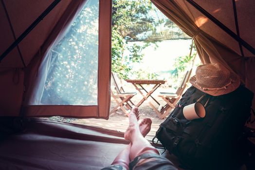 view of crossed feet of a hiker man resting barefoot in a camping tent, travel discovery concept, point of view shot