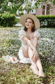 An attractive long-haired woman walks in the spring in the park of blooming apple trees. Spring portrait of a woman