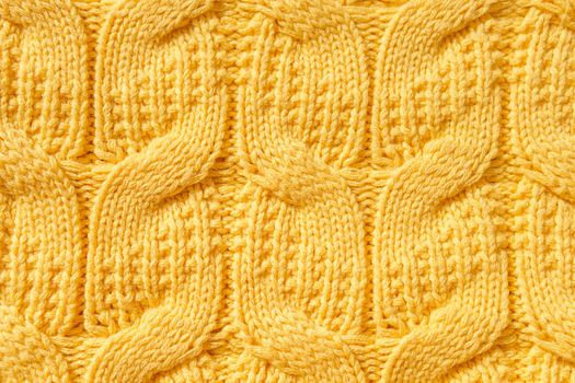 The texture of a warm knitted sweater. The perfect background is yellow. Close-up.