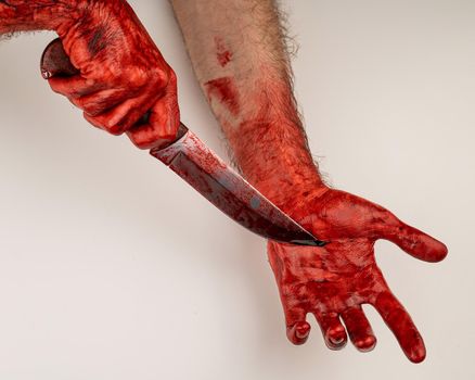 A man with bloody hands cuts himself with a knife