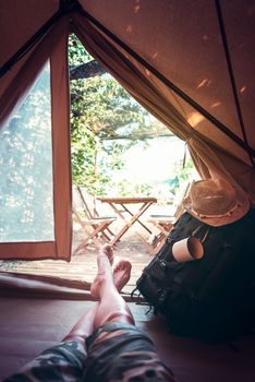 vertical view of crossed feet of a hiker man resting barefoot in a camping tent, travel discovery concept, point of view shot