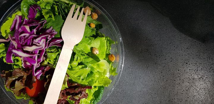 Healthy vegetable salad of fresh tomato, lettuce and red cabbage with wooden spoon and caesar salad dressing Diet menu Top view