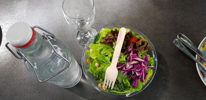 Healthy vegetable salad of fresh tomato, lettuce and red cabbage with wooden spoon and caesar salad dressing Diet menu Top view