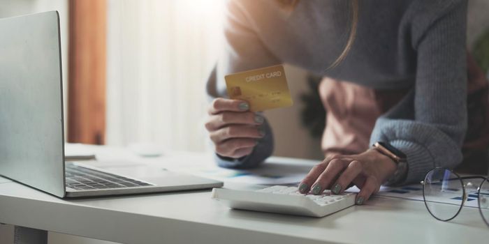 Close up man using calculator and holding credit card at home..