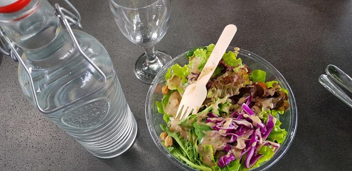 Healthy vegetable salad of fresh tomato, lettuce and red cabbage with wooden spoon and caesar salad dressing Diet menu Top view