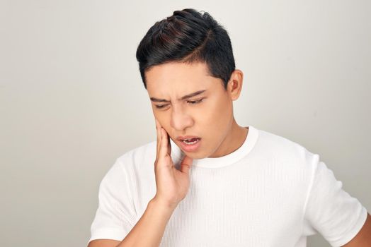 Portrait of Asian men with worry eyes use hand touching his cheek , feelings pain from toothache. Tooth and mouth disease concept.