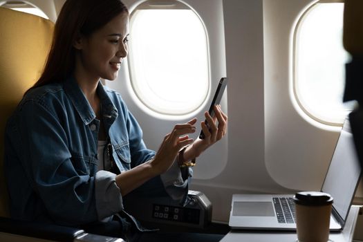 Beautiful asian travel woman using mobile phone in airplane