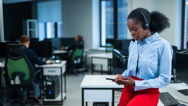 African female call center employee using smartphone