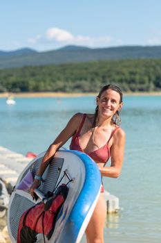 Woman Paddle Surfing on Lake Montbel in Ariege with the boats in the summer of 2022.