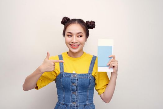 Attractive excited woman 20s smiling while holding passport with travel tickets isolated over white background