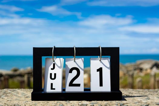 Jul 21 calendar date text on wooden frame with blurred background of ocean. Calendar date concept.