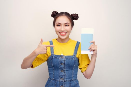 Attractive excited woman 20s smiling while holding passport with travel tickets isolated over white background