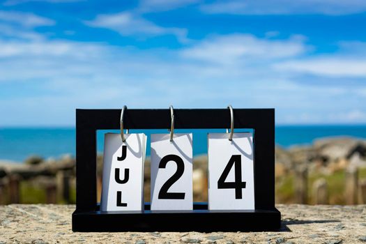 Jul 24 calendar date text on wooden frame with blurred background of ocean. Calendar date concept.