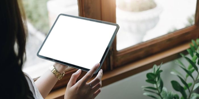 Mockup image of a woman holding digital tablet with blank white desktop screen.