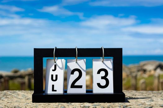 Jul 23 calendar date text on wooden frame with blurred background of ocean. Calendar date concept.