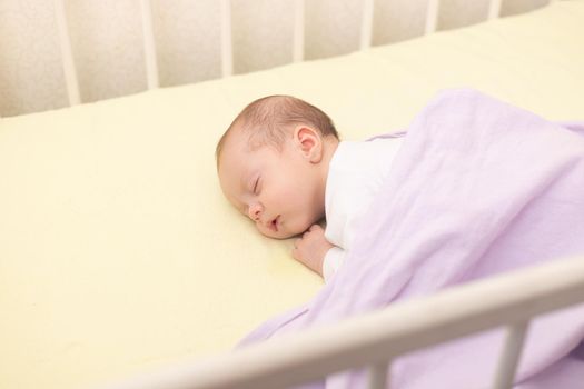 The baby sleeps in the copy space crib . Advertising of children's goods. Illustrating children's articles. A small child. A newborn. A child's dream.