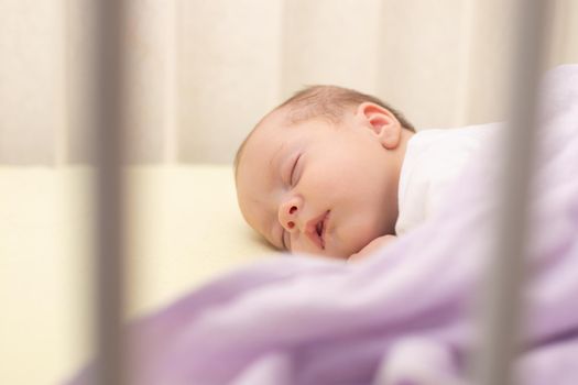 The baby sleeps in the copy space crib . Advertising of children's goods. Illustrating children's articles. A small child. A newborn. A child's dream.