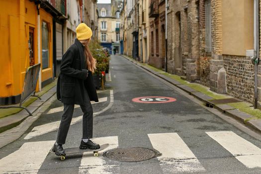 A girl in a yellow hat with a skateboard in the city