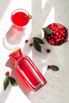 Cold cherry juice in a glass and bottle with ripe berries. Top view, The concept of summer refreshing drink morse or kompot.