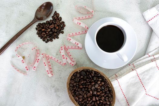 Cup of coffee and coffee beans background with measure tap on white desk. Beverage and diet concept. Directly above. Flat lay. Copy space.